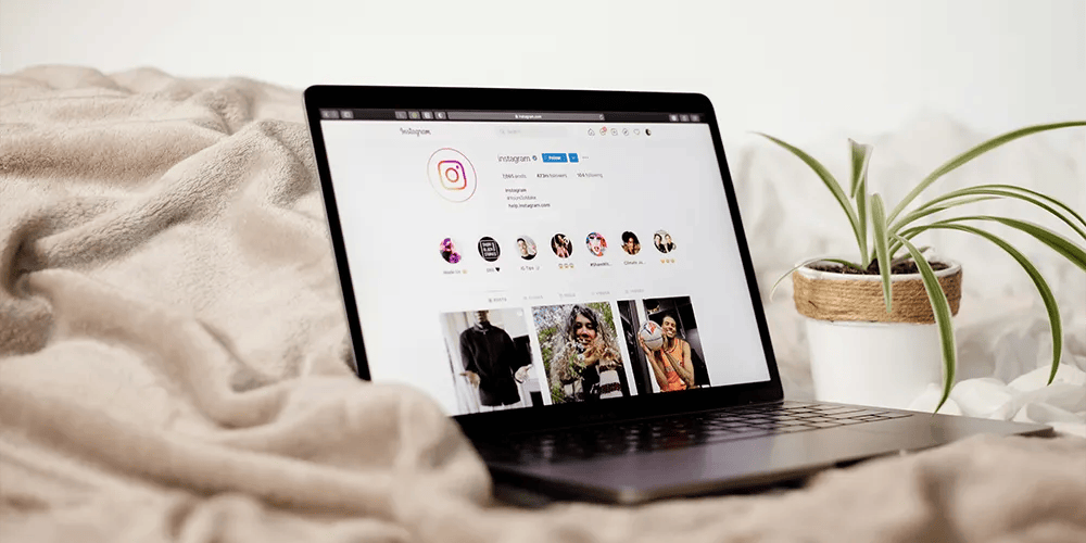 Laptop showing a social media feed on a bed