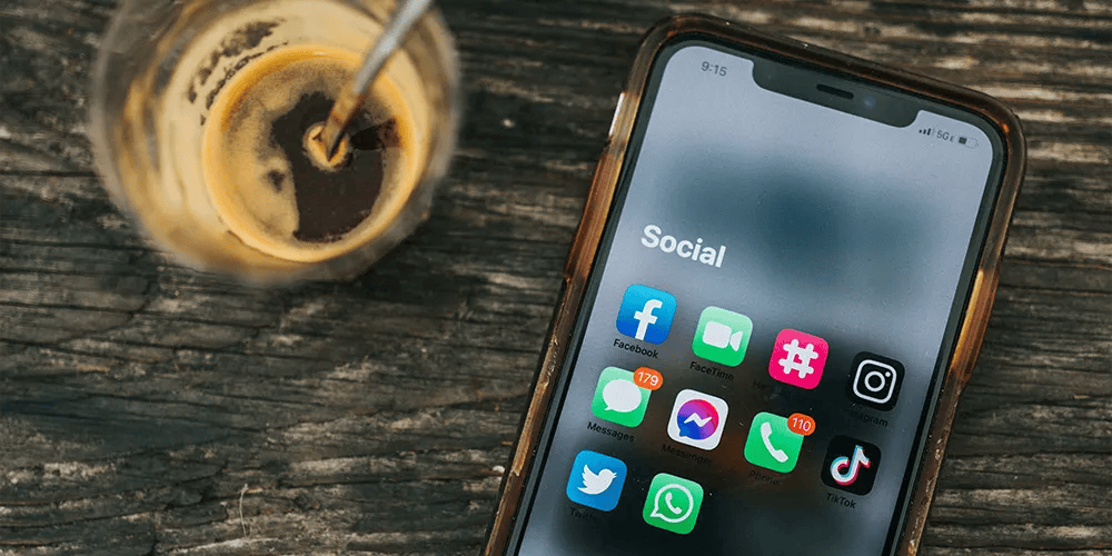 Phone showing social apps beside an iced coffee